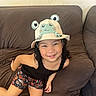 Zackary joined the competition — help win amazing prizes! child, smiling, hat, frog, brown_couch, indoor, black_tank_top, shorts, playful, cute, happy, person, curly_hair, casual, leisure, cozy, home, furniture, portrait, bright
