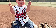 Canaan is registered to the contest to win money with this photo: toddler, child, baseball, baseball_glove, baseball_field, sportswear, sneakers, jeans, jersey, outdoor, sunny, grass, dirt, playing, happy, sitting, young_child, sports_equipment, daytime, recreation