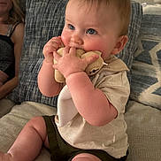 Canaan is registered to the contest to win money with this photo: baby, child, infant, stuffed_toy, couch, cushion, person, sitting, indoors, home, soft_toy, blue_eyes, shorts, tshirt, cute, chubby, furniture, adult, woman, lamp