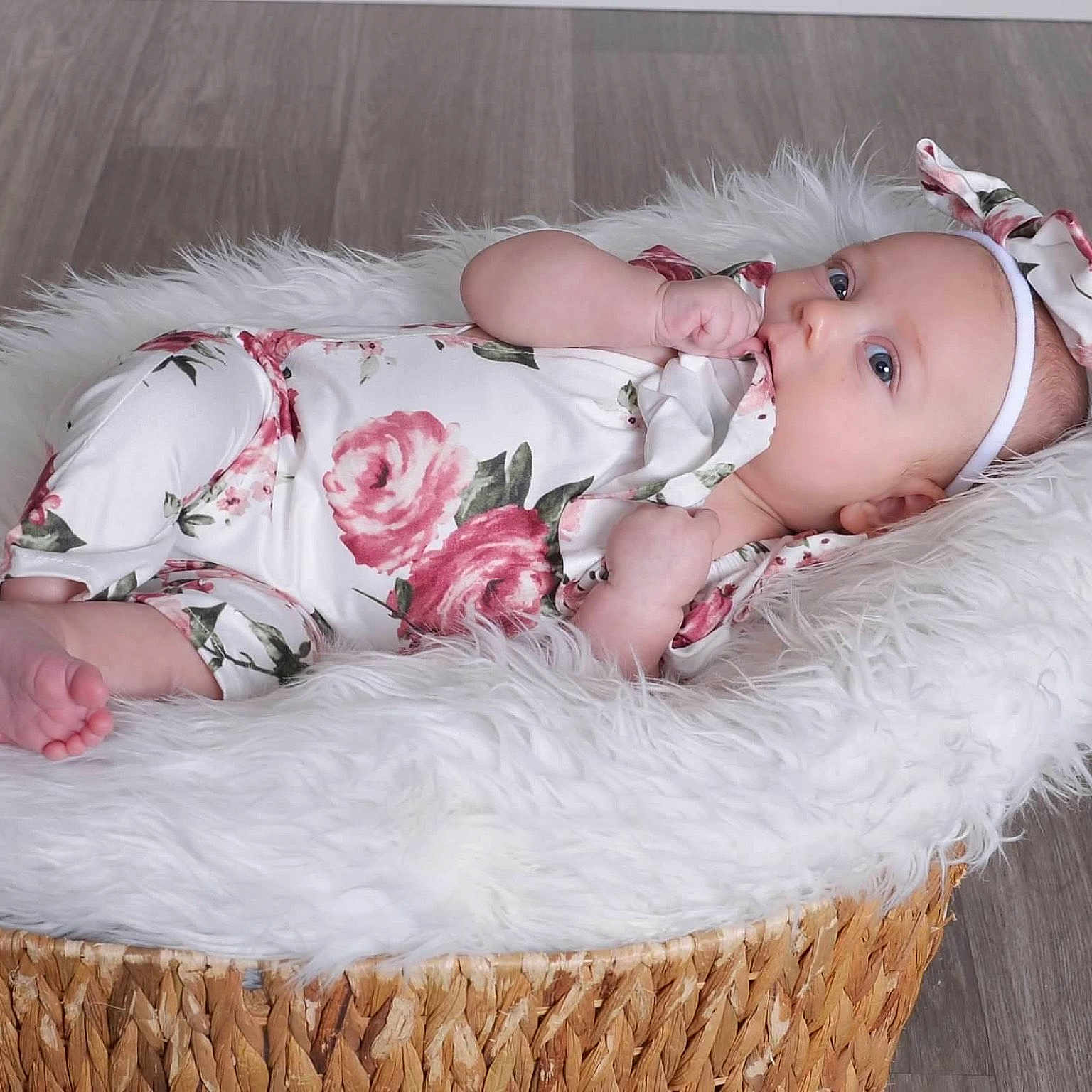 Rhilley joined the competition — help win amazing prizes! baby, baby_clothing, basket, blue_eyes, chewing, child, cute, floor, floral_onesie, headband, indoors, infant, lying_down, newborn, peaceful, portrait, relaxed, soft_texture, toddler, white_fur