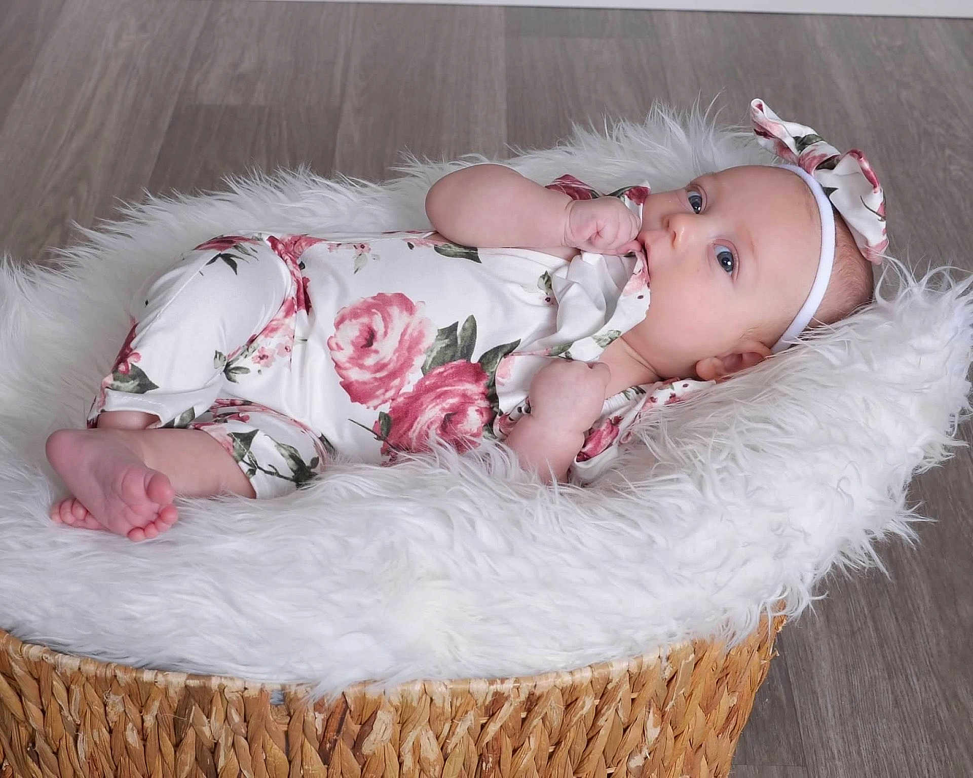 Rhilley joined the competition — help win amazing prizes! baby, infant, floral_onesie, headband, basket, white_fur, floor, blue_eyes, chewing, cute, newborn, soft_texture, portrait, indoors, relaxed, baby_clothing, child, toddler, lying_down, peaceful