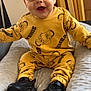 Këyden participe au concours pour gagner de l'argent avec cette photo : baby, smiling, yellow_clothing, simba, sitting, cushion, indoors, happy, child, footwear, black_shoes, cute, portrait, infant, comfortable, soft_texture, expression, person, clothing_pattern, head