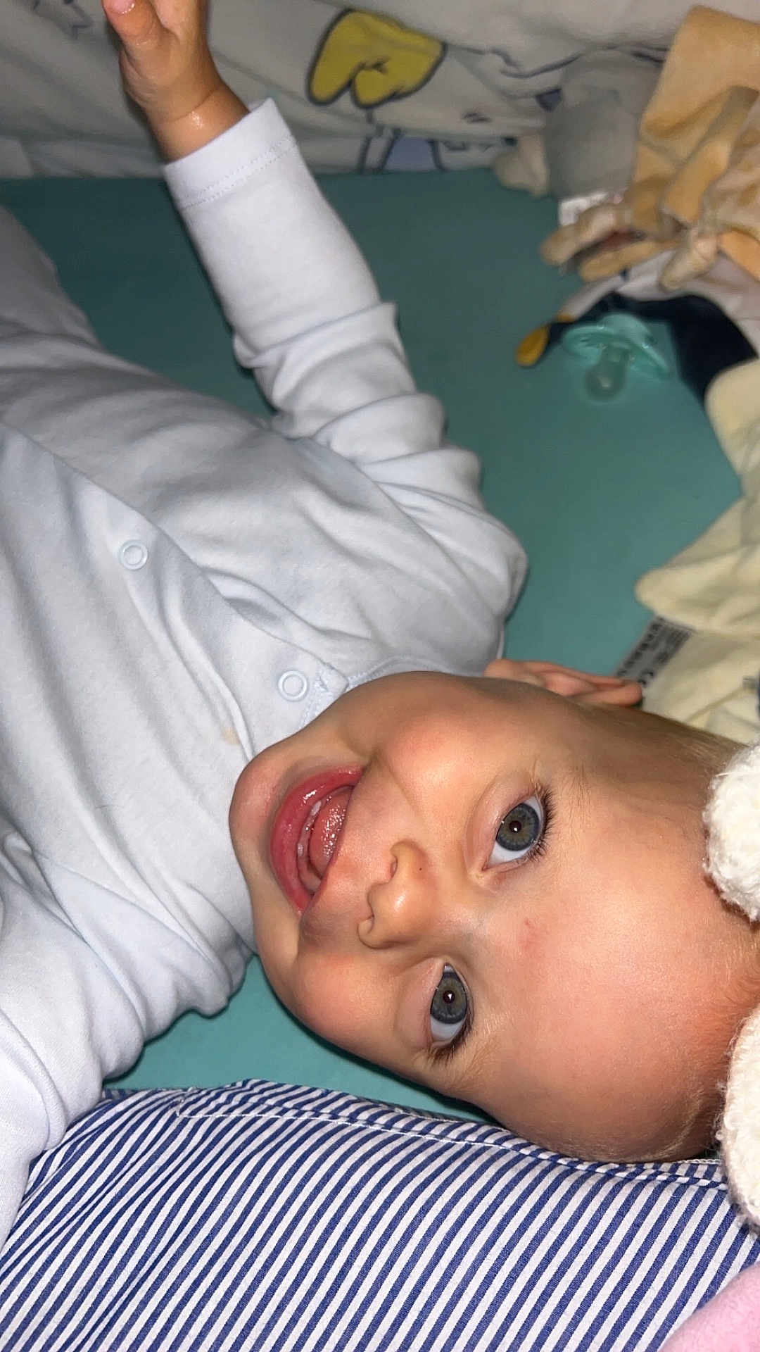 Këyden a rejoint le concours — aidez-le/la à gagner de superbes lots ! baby, infant, smiling, happy, lying_down, onesie, striped_pillow, blanket, pacifier, child, cute, face, head, closeup, indoors, soft_toys, skin, expression, young_child, playful
