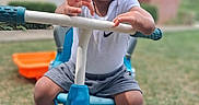 Robert joined the competition — help win amazing prizes! toddler, child, tricycle, outdoor, grass, curly_hair, shorts, sneakers, white_shirt, handlebars, serious_expression, playground_toy, suburban, daylight, person, footwear, seat, front_view, toy_vehicle, summer