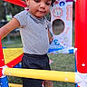 Robert joined the competition — help win amazing prizes! toddler, child, playground, play_structure, outdoor, colorful, red, yellow, blue, grass, lion_illustration, shorts, tshirt, curly_hair, footwear, toy, daylight, person, casual_clothing, focused