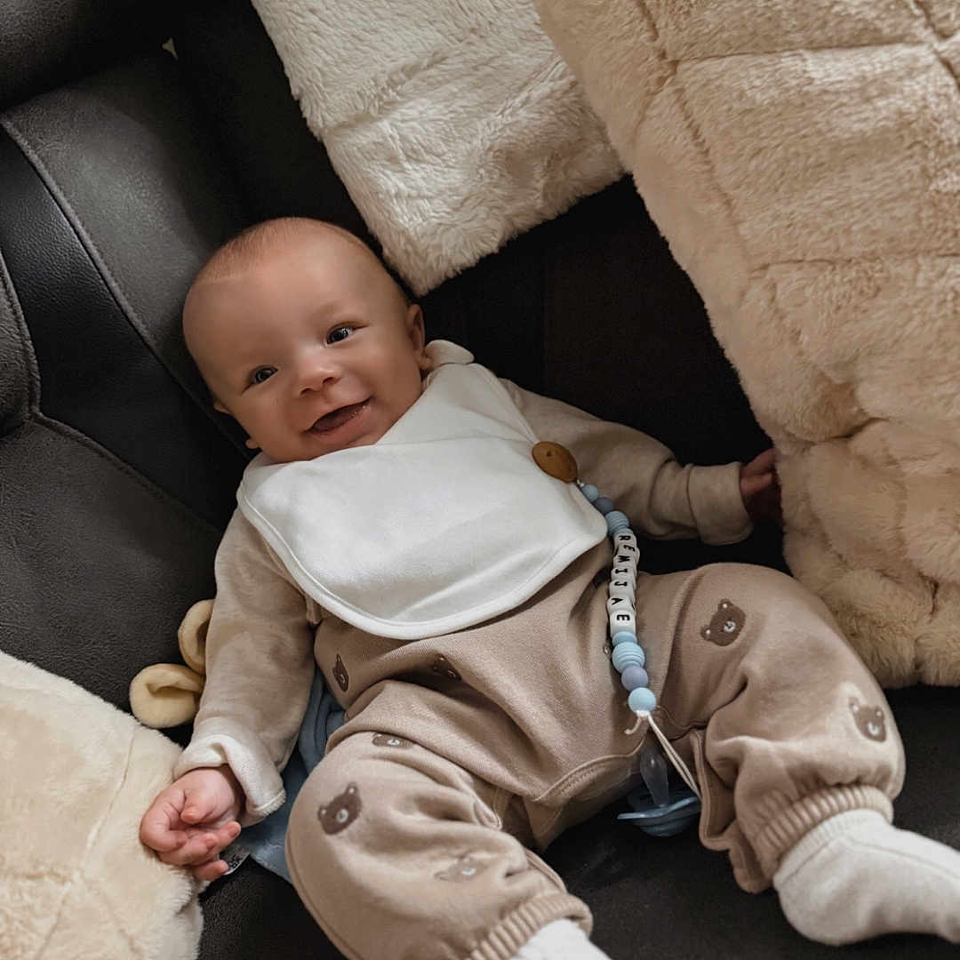 Remi Jae is registered to the contest to win money with this photo: baby, bib, blanket, child, clothing, comfort, couch, cozy, cute, face, happy, indoors, infant, pacifier, pillow, relaxing, smile, socks, soft, toy