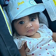 Jeev joined the competition — help win amazing prizes! baby, child, face, hat, cap, bunny_ears, car_seat, clothing, white_outfit, ladybug_print, cute, portrait, infant, seatbelt, indoors, person, closeup, expression, young_child, sitting