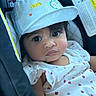 baby, child, face, hat, cap, bunny_ears, car_seat, clothing, white_outfit, ladybug_print, cute, portrait, infant, seatbelt, indoors, person, closeup, expression, young_child, sitting