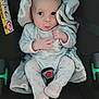 baby, car_seat, blanket, onesie, infant, expression, seatbelt, polka_dot, child, cute, indoors, person, clothing, sitting, young, head, face, hand, footwear, safety
