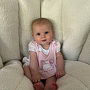 Georgia is registered to the contest to win money with this photo: baby, infant, child, pink_bib, unicorn, blue_eyes, fluffy_chair, cozy, cute, sitting, clothing, indoor, portrait, soft_texture, small_feet, curious_expression, person, young_child, comfortable, home
