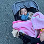 baby, blanket, casual, child, clothing, comfort, cozy, cute, daytime, hand, infant, outdoor, pavement, person, stroller, thumb_sucking, transportation, walking, warm, wheel