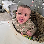 Ayah is registered to the contest to win money with this photo: baby, blanket, child, clothing, couch, cute, expression, face, floral_pattern, furniture, happy, high_chair, home, indoor, infant, person, portrait, sitting, smile, young_child