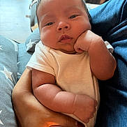 Hugo is registered to the contest to win money with this photo: baby, infant, arm, hand, onesie, person, face, skin, fingers, couch, fabric, comfort, cute, expression, holding, newborn, portrait, indoor, closeup, soft