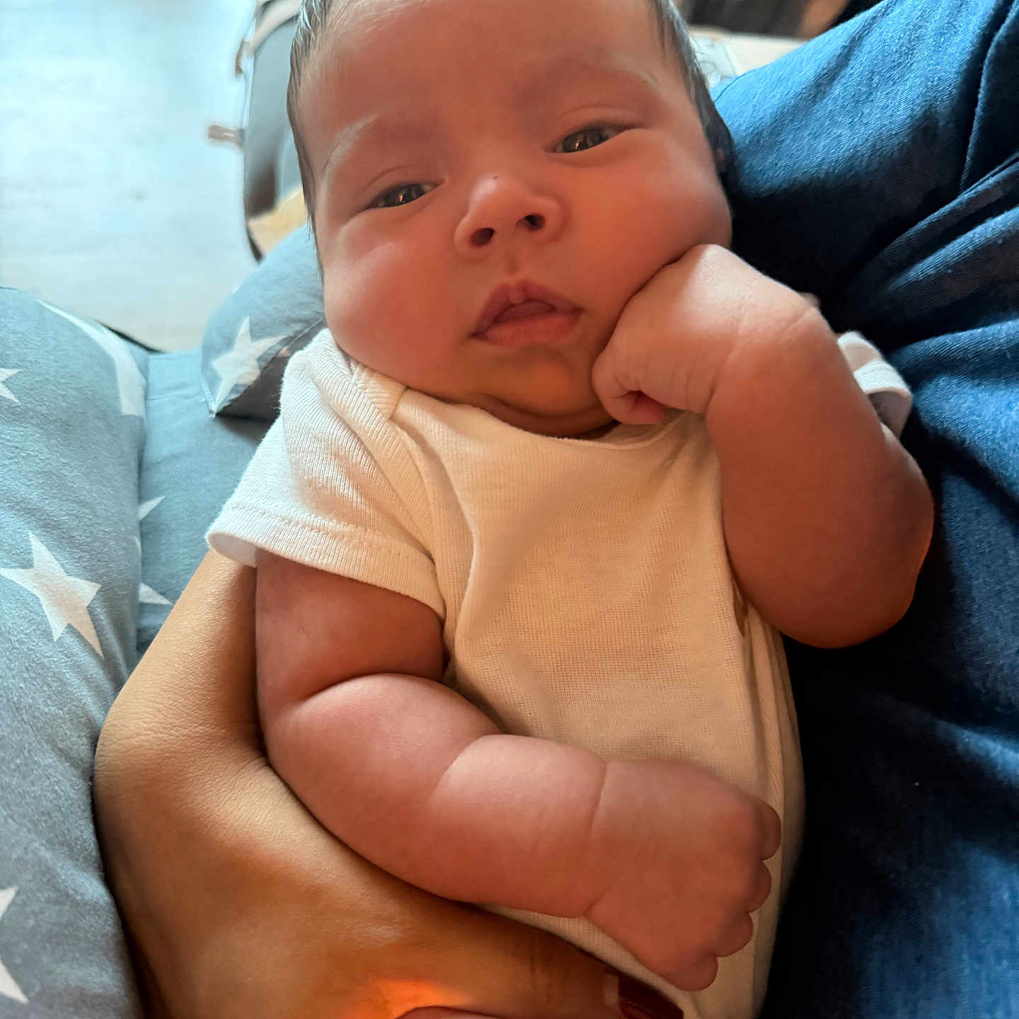 Hugo is registered to the contest to win money with this photo: baby, infant, arm, hand, onesie, person, face, skin, fingers, couch, fabric, comfort, cute, expression, holding, newborn, portrait, indoor, closeup, soft