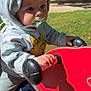 baby, child, clothing, cute, daytime, expression, face, grass, hand, hoodie, infant, outdoor, pacifier, park, person, playground, red, spring_rider, sunlight, toy