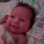 Grace joined the competition — help win amazing prizes! baby, smile, blanket, pillow, face, infant, hair, cute, child, lying_down, expression, skin, person, newborn, happy, indoors, towel, colorful, pattern, soft