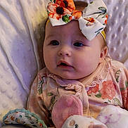 Grace is registered to the contest to win money with this photo: baby, infant, child, bow, headband, floral, onesie, plush_toy, stuffed_animal, blanket, bedding, portrait, closeup, cheeks, eyes, gaze, cozy, nursery, pink, soft_texture