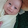 baby, infant, smile, blanket, wrapped, teddy_bear, plush_toy, hand, face, blue_eyes, soft_texture, cozy, cute, indoor, portrait, young_child, newborn, expression, lying_down, warm