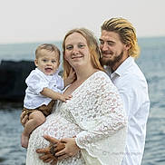 Dylan Jr is registered to the contest to win money with this photo: baby, child, family, parents, mother, father, smiling, portrait, outdoor, seaside, ocean, water, beach, lace_dress, white_clothing, infant, holding_child, family_photo, tattoo, photography