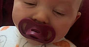 Madalynn is registered to the contest to win money with this photo: baby, infant, sleeping, pacifier, portrait, close_up, face, child, onesie, clothing, blanket, bed, indoor, home, cartoon, lizard, green, toy, cute, resting