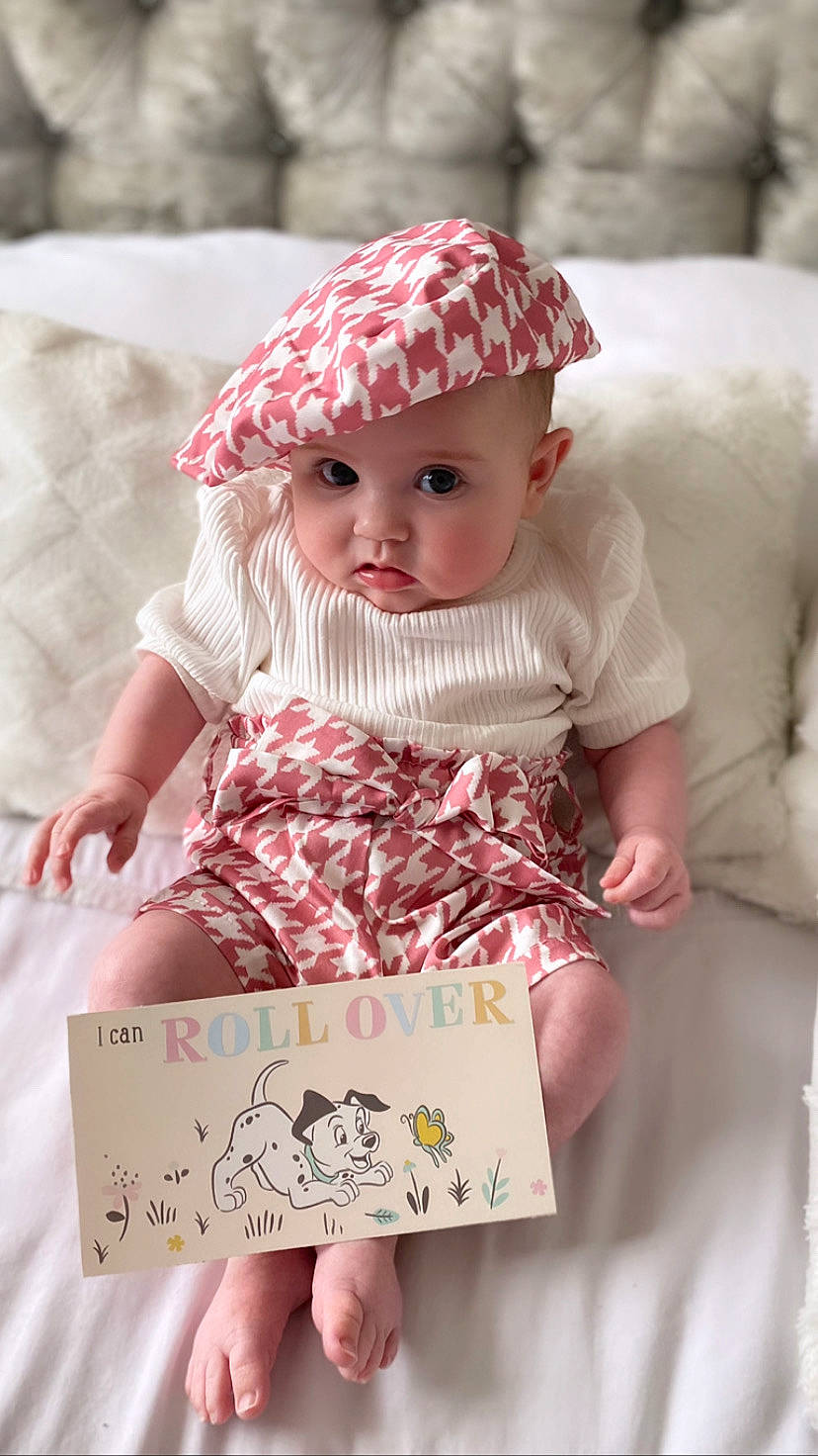 Cathy is registered to the contest to win money with this photo: baby_toddler_clothing, beauty, cap, child, doll, dress, eyelash, fashion, fashion_design, happy, headwear, lip, pattern, peach, person, pink, skin, sleeve, textile, toy