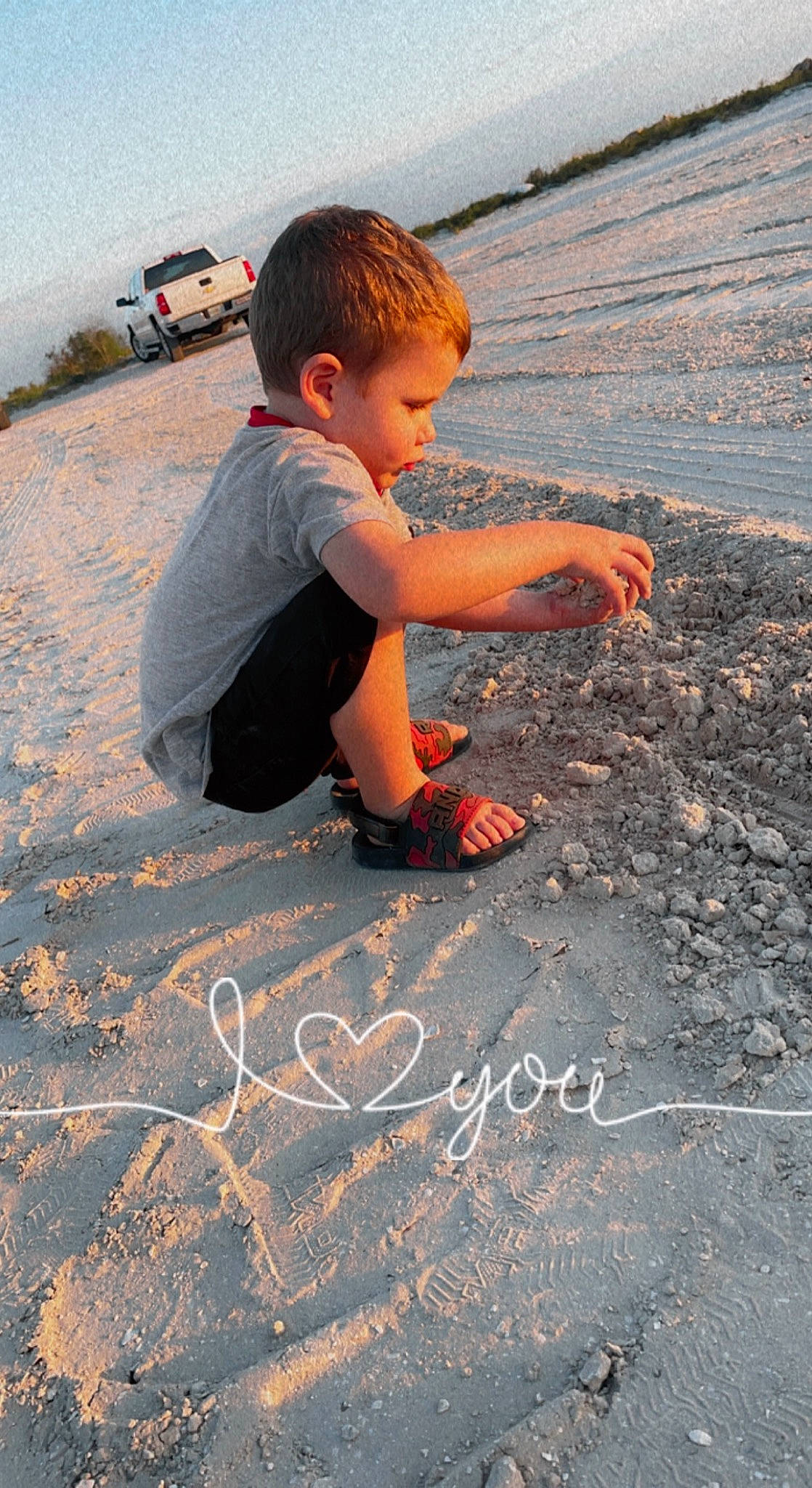 Angel is registered to the contest to win money with this photo: asphalt, car, child, flooring, font, fun, grass, handwriting, happy, landscape, leisure, person, road_surface, sand, shadow, sidewalk, sitting, soil, t_shirt, toddler