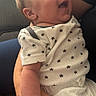 David is registered to the contest to win money with this photo: baby, infant, child, smiling, happy, portrait, close_up, sitting, being_held, adult, caregiver, onesie, star_pattern, white_clothing, baby_clothing, indoor, natural_light, car_seat, candid, face