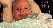 David joined the competition — help win amazing prizes! baby, newborn, infant, car_seat, blanket, plush_cushion, portrait, face, smiling, sitting, indoors, vehicle, travel, cozy, mint_green, soft_blanket, head_support, safety_label, close_up, child