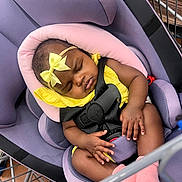 Zanaija Tate joined the competition — help win amazing prizes! baby, infant, sleeping, car_seat, yellow_clothing, pink_bow, pink_socks, black_harness, shopping_cart, purple_cushion, child, cute, peaceful, indoors, person, toddler, resting, seatbelt, head_support, small_child