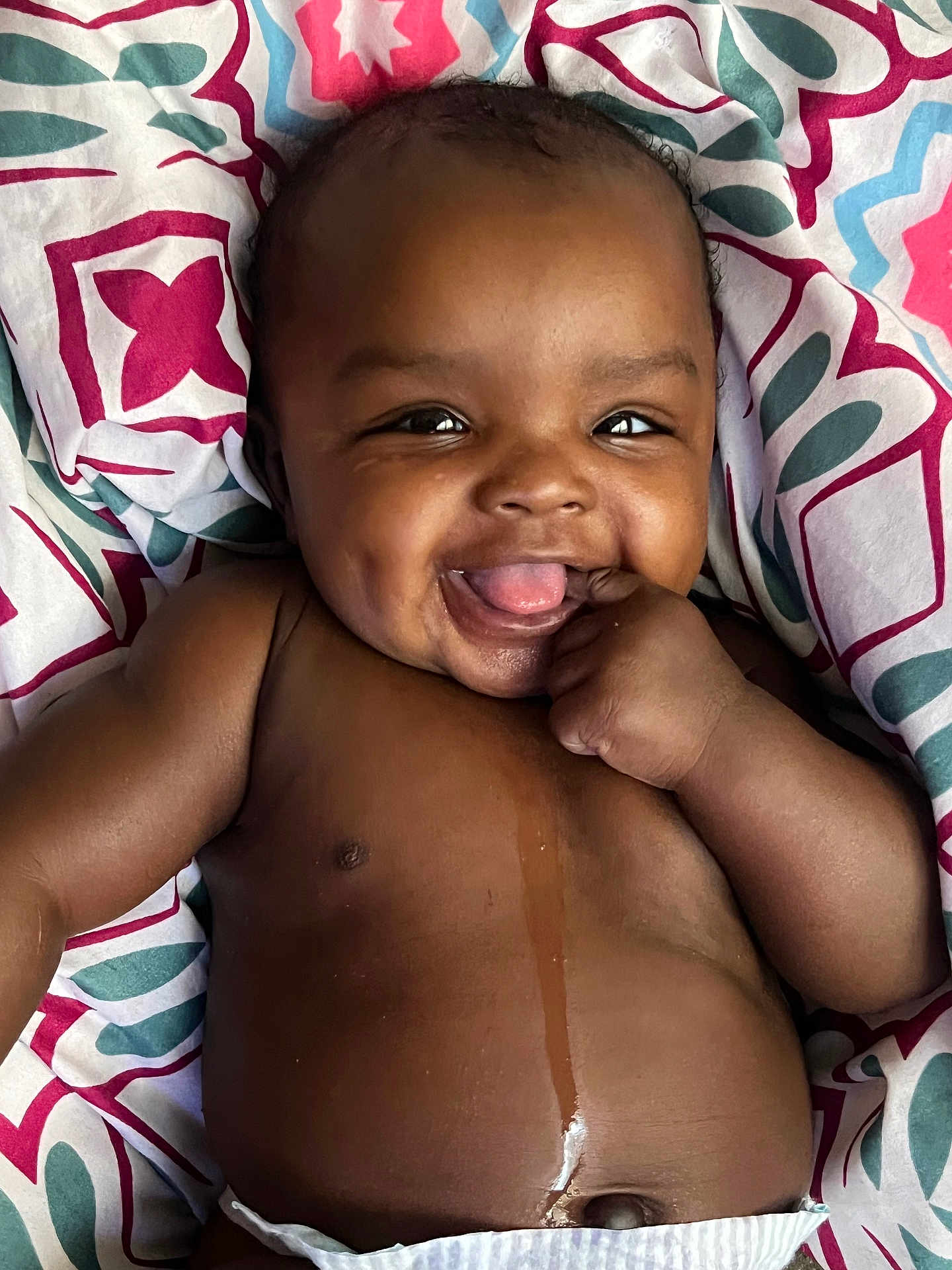 Zanaija Tate joined the competition — help win amazing prizes! baby, smiling, infant, child, happy, face, skin, hand, diaper, blanket, pattern, colorful, lying_down, cute, portrait, young, playful, expression, indoors, closeup