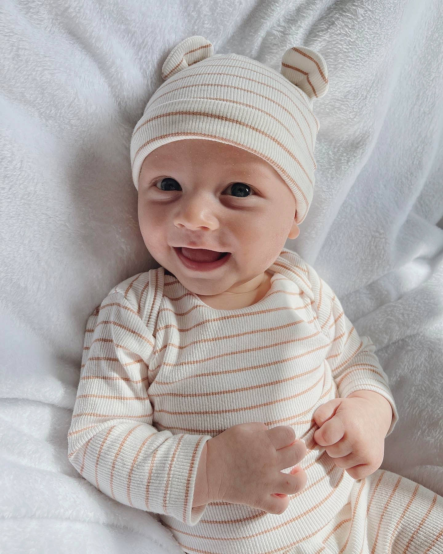 Brooks is registered to the contest to win money with this photo: baby, baby_toddler_clothing, beanie, cap, child, chin, collar, comfort, fashion_accessory, headgear, headwear, knit_cap, linens, pattern, person, portrait_photography, sleeve, smile, toddler, white