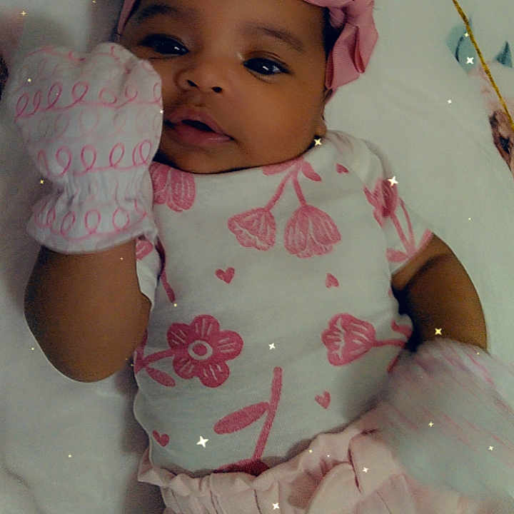 Emerlee is registered to the contest to win money with this photo: adorable, baby, bed, child, cute, floral_pattern, headband, indoor, infant, lying_down, mittens, phone_ui, pink_clothing, portrait, sleepwear, small, snapshot, soft_lighting, starry_filter, young