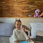 Melina a rejoint le concours — aidez-le/la à gagner de superbes lots ! toddler, child, book, bed, pigtails, stuffed_animal, toy, zebra_toy, wooden_wall, pillow, blanket, indoors, cute, smiling, white_clothing, girl, home, cozy, sitting, playful