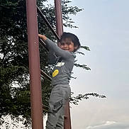 Ezequiel is registered to the contest to win money with this photo: child, climbing, ladder, outdoor, tree, sky, cloud, streetlight, smile, nike, clothing, sneakers, playground, person, evening, activity, nature, metal, casual, fun