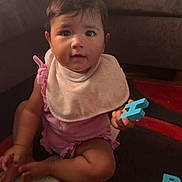 Maria joined the competition — help win amazing prizes! baby, child, indoor, carpet, alphabet_letters, toy, bib, sitting, curious, colorful, foam_letters, couch, floor, playtime, infant, young_child, pink_clothing, hand, foot, expression