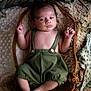 baby, infant, green_clothing, suspenders, wooden_swing, blanket, fur_texture, indoor, cute, child, newborn, face, hands, feet, expression, soft_lighting, decor, plant, portrait, relaxed