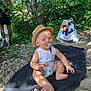 baby, pacifier, hat, towel, outdoor, nature, tree, rocks, bag, diaper, child, greenery, sunlight, shade, person, adult, summer, relaxation, casual, barefoot