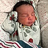 newborn, baby, sleeping, infant, face, portrait, blanket, swaddled, floral, fabric, nursery, indoors, peaceful, closed_eyes, dark_hair, lying_down, cozy, photography, bedding, resting