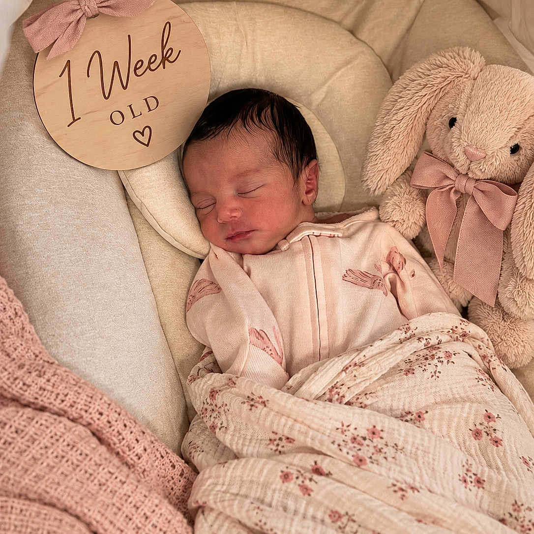 Auralise joined the competition — help win amazing prizes! newborn, baby, sleeping, infant, portrait, blanket, swaddle, plush_toy, bunny, nursery, milestone, one_week, cozy, indoors, soft_lighting, pink, beige, floral, wooden_sign, peaceful