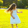 Maria Alice is registered to the contest to win money with this photo: child, girl, outdoor, meadow, grass, park, sunlight, sunny, portrait, floral_dress, long_hair, flying_hair, smiling, running, twirling, garden, trees, nature, daytime, shoes