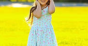 Maria Alice is registered to the contest to win money with this photo: child, girl, smiling, portrait, outdoor, meadow, grass, sunlight, summer, floral_dress, long_hair, standing, posing, park, nature, backlighting, sunny, happy, shoes, photography
