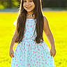 backlighting, child, daylight, dress, family_photo, floral_dress, girl, grass, greenery, happy, long_hair, meadow, nature, necklace, outdoor, person, portrait, smiling, standing, sunlight