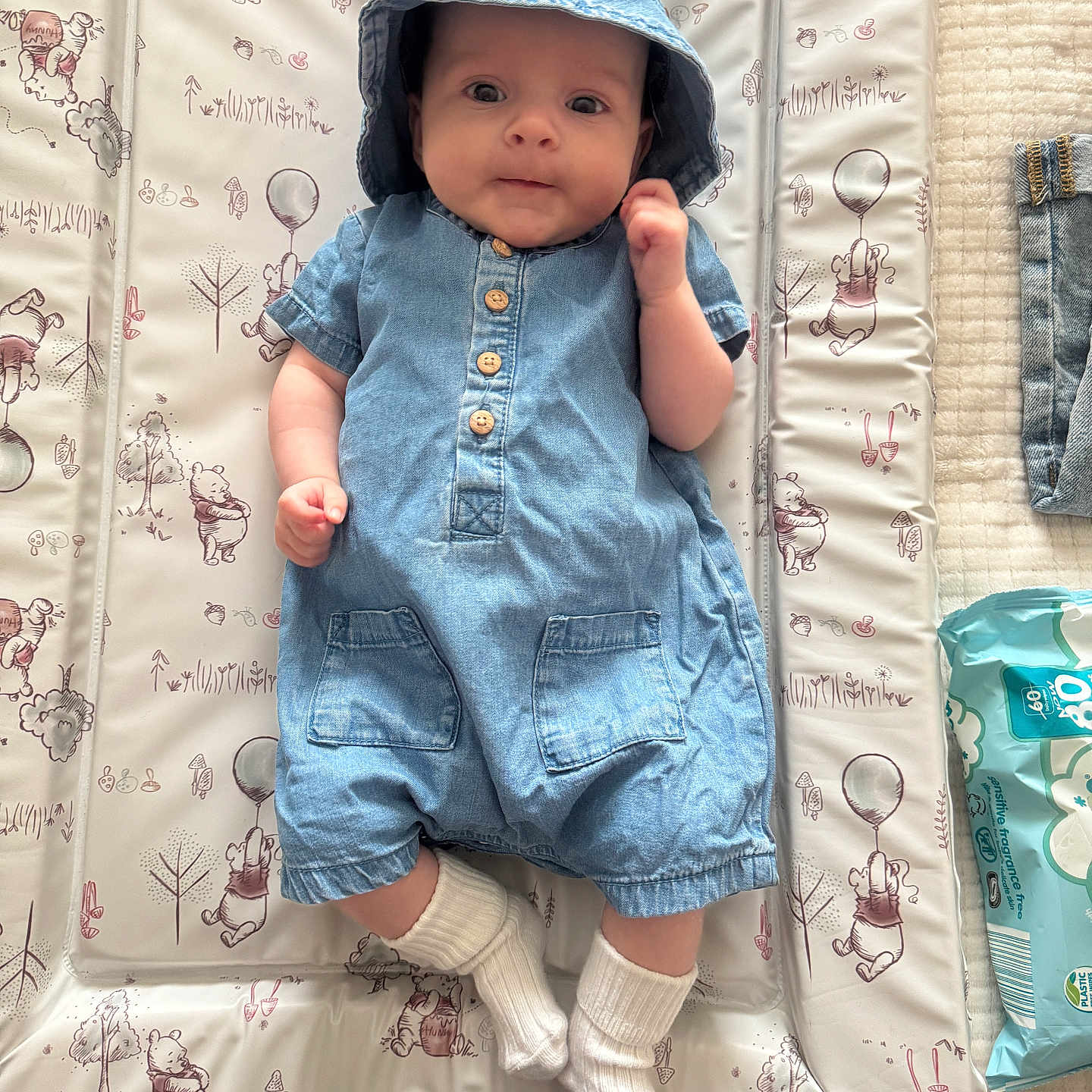 Evie Grace is registered to the contest to win money with this photo: baby, baby_boy, baby_girl, bucket_hat, changing_pad, child, clothing, cute, denim, fabric, floor, indoor, infant, patterned_background, portrait, romper, smiling, soft_lighting, white_socks, winnie_the_pooh