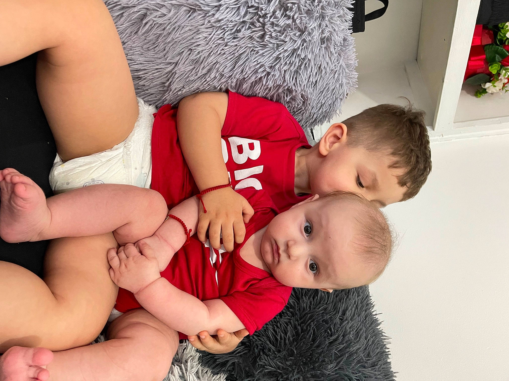 Robert is registered to the contest to win money with this photo: arm, baby_toddler_clothing, comfort, facial_expression, gesture, hairstyle, happy, human_body, interaction, joint, knee, leg, muscle, neck, organ, person, picture_frame, red, shoulder, skin