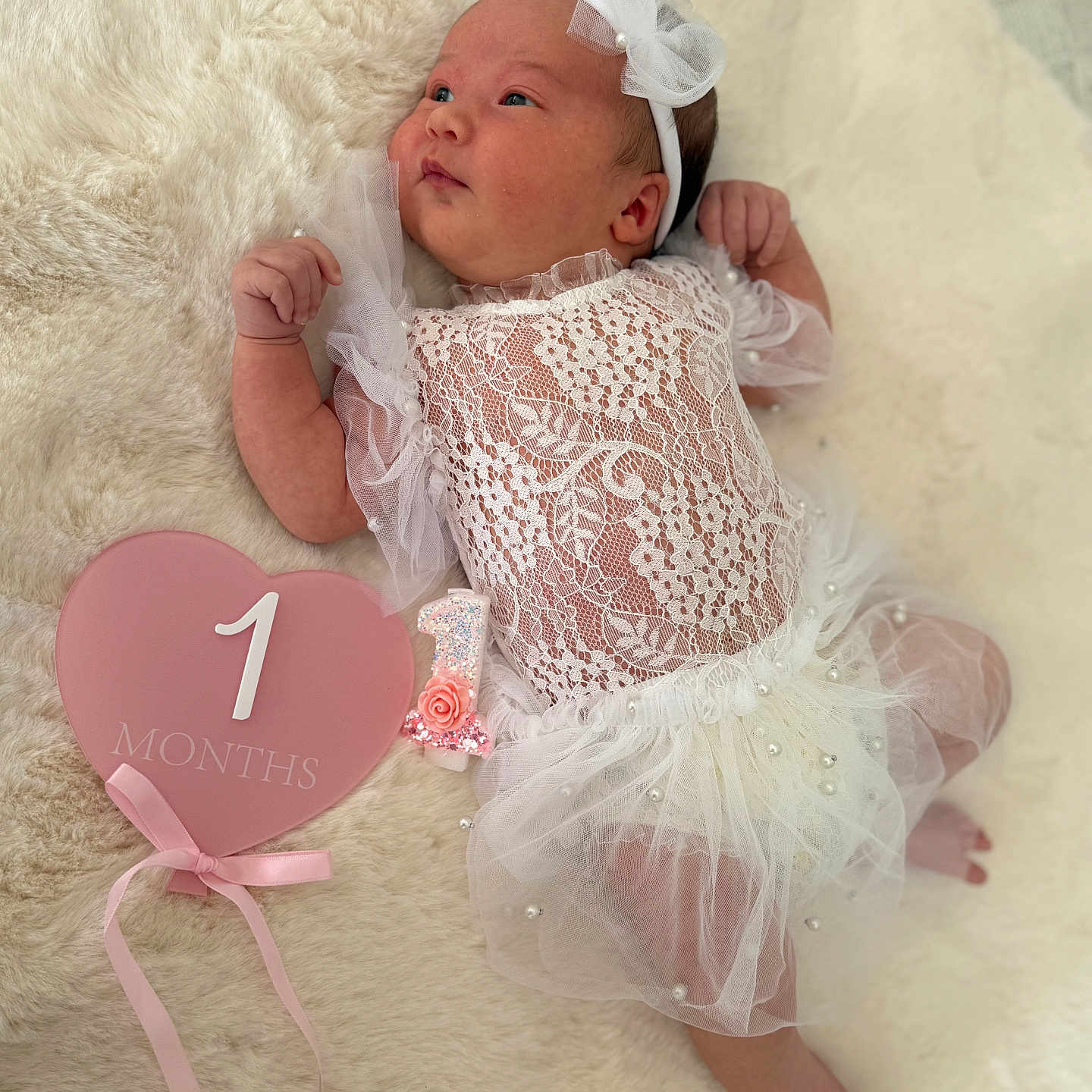Anná participe au concours pour gagner de l'argent avec cette photo : baby, baby_girl, blanket, celebration, cute, headband, heart_shape, indoor, infant, lace_dress, lying_down, milestone, newborn, number_one_candle, one_month, pearls, pink_sign, portrait, soft_texture, white_clothing