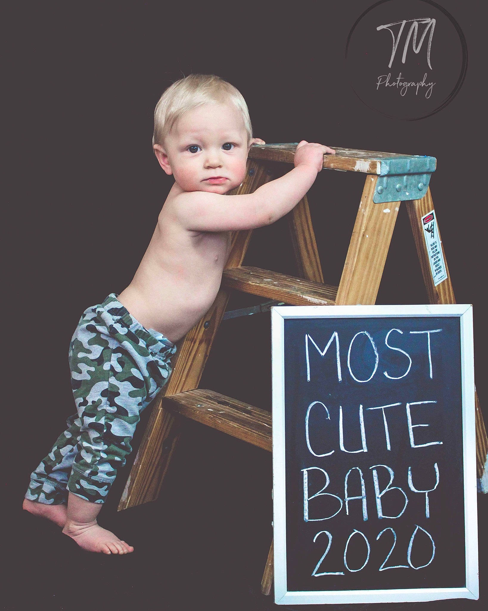 Mackinnon is registered to the contest to win money with this photo: blackboard, chalk, child, child_model, easel, office_supplies, person, photography, room, t_shirt, toddler