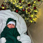 𝘓𝘢𝘩𝘪𝘢𝘮 joined the competition — help win amazing prizes! baby, child, christmas_tree, holiday, ornaments, lights, green_clothing, blanket, white, nike, headwear, socks, shoes, indoor, decorations, festive, cute, infant, smiling, cozy