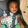 baby, child, car_seat, safety_harness, toy, animal_print, giraffe, elephant, smile, happy, infant, green_pants, gray_shirt, seat_belt, cute, portrait, indoor, close_up, hand, face