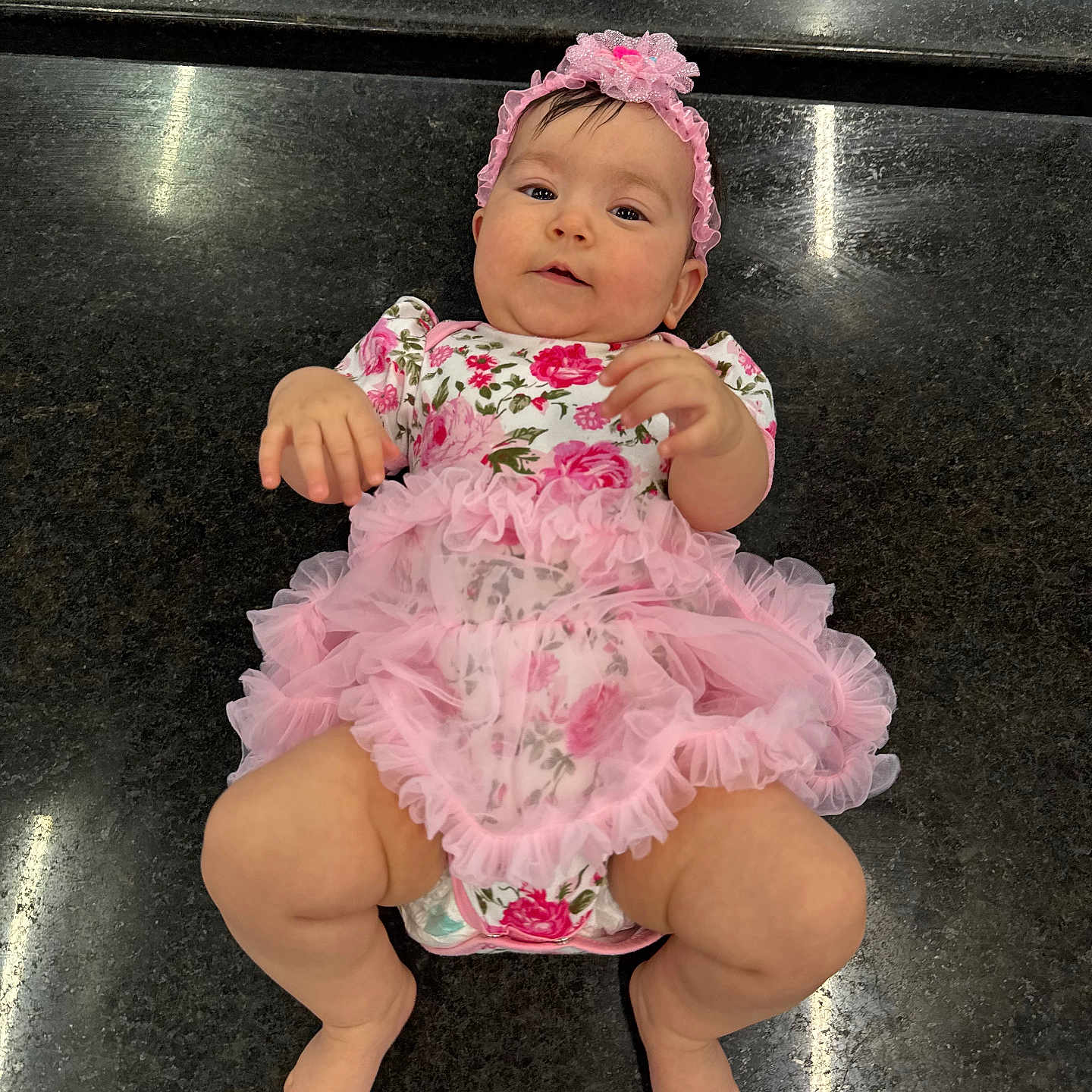 Heisy Ailany joined the competition — help win amazing prizes! baby, baby_girl, barefoot, child, chubby_legs, clothing, cute, floor, floral_pattern, hands, headband, indoor, infant, looking_up, lying_down, one_person, pink_dress, portrait, skin, smiling