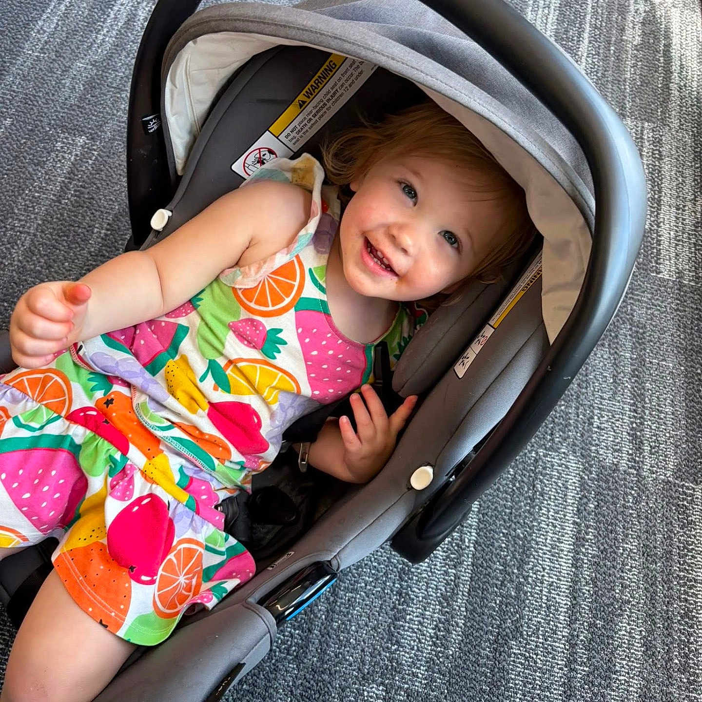 Wrenly joined the competition — help win amazing prizes! toddler, child, baby, smiling, happy, portrait, car_seat, infant_carrier, colorful_clothing, fruit_pattern, dress, red_hair, blue_eyes, lying_down, indoor, carpet, handle, safety_strap, playful, photography